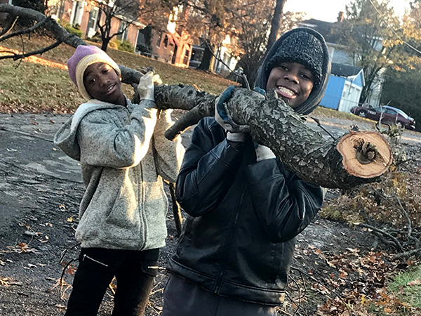 two young male volunteers carrying wood